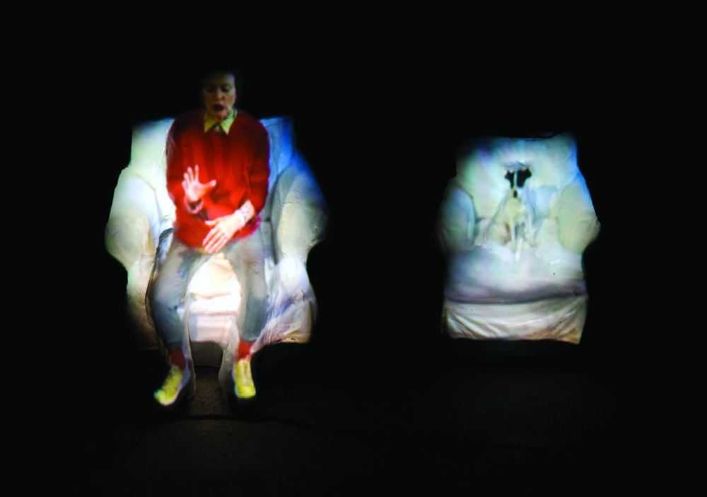 Still from Laurie Anderson's video work "From the Air" showing herself projected onto clay figures